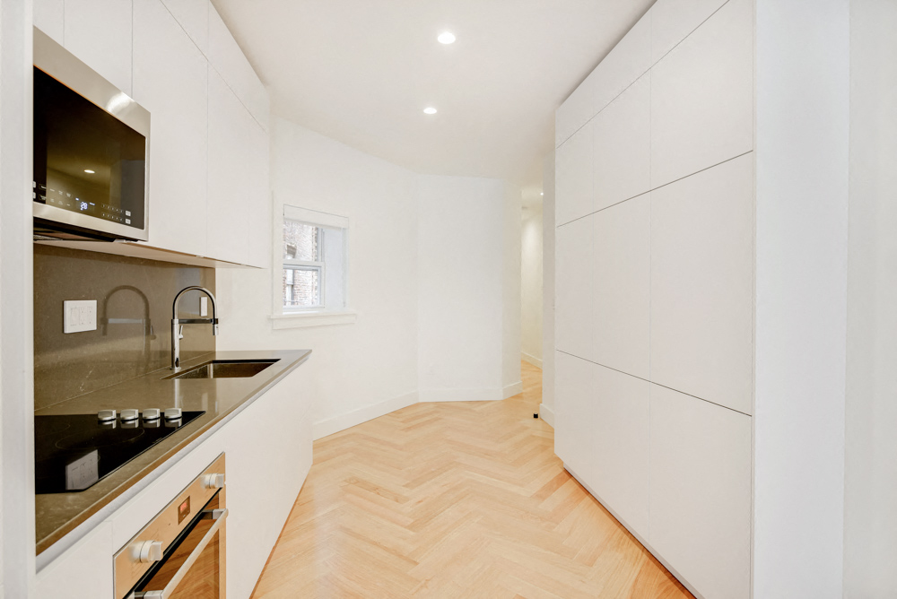 a kitchen with white cabinets and a wood floor
